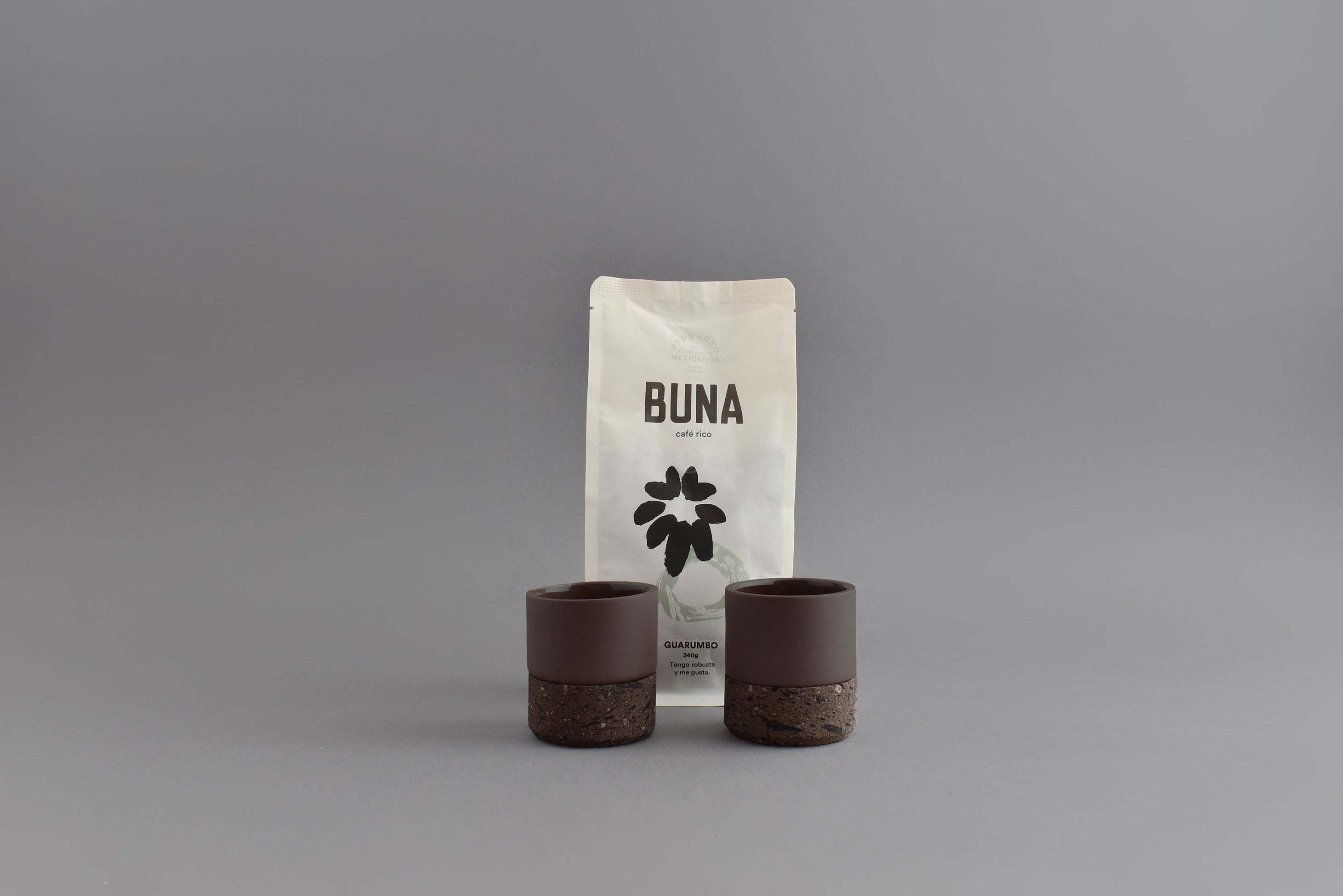 Dos vasos de cerámica café para espresso junto a una bolsa de café Buna